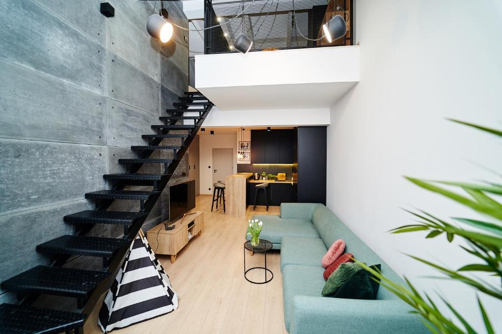 a living room with a blue couch and a staircase at LOFT Apartment in Suwałki