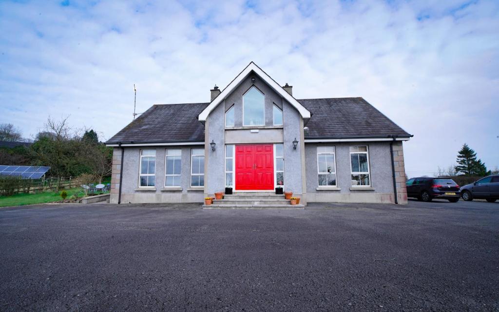 uma casa com uma porta vermelha num parque de estacionamento em Glenburn Galgorm Bed & Breakfast em Galgorm