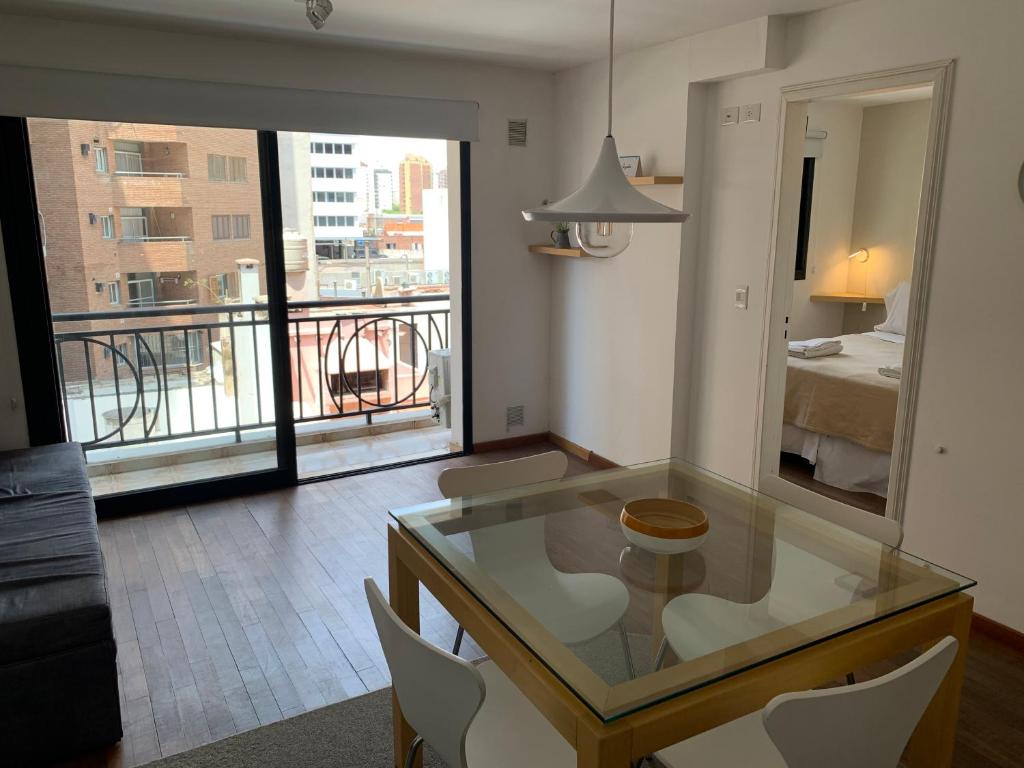 a living room with a glass table and a balcony at Guemes Apart Nueva Cordoba in Cordoba