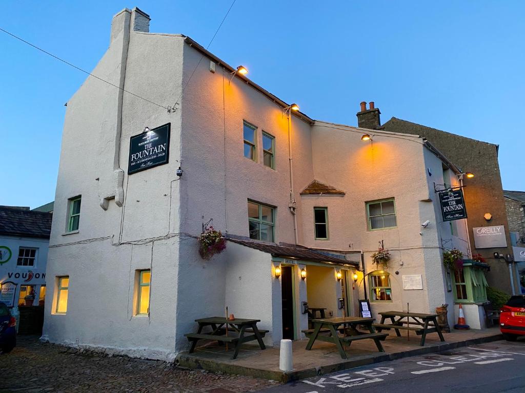 a building with picnic tables in front of it at The Fountain Hotel in Hawes