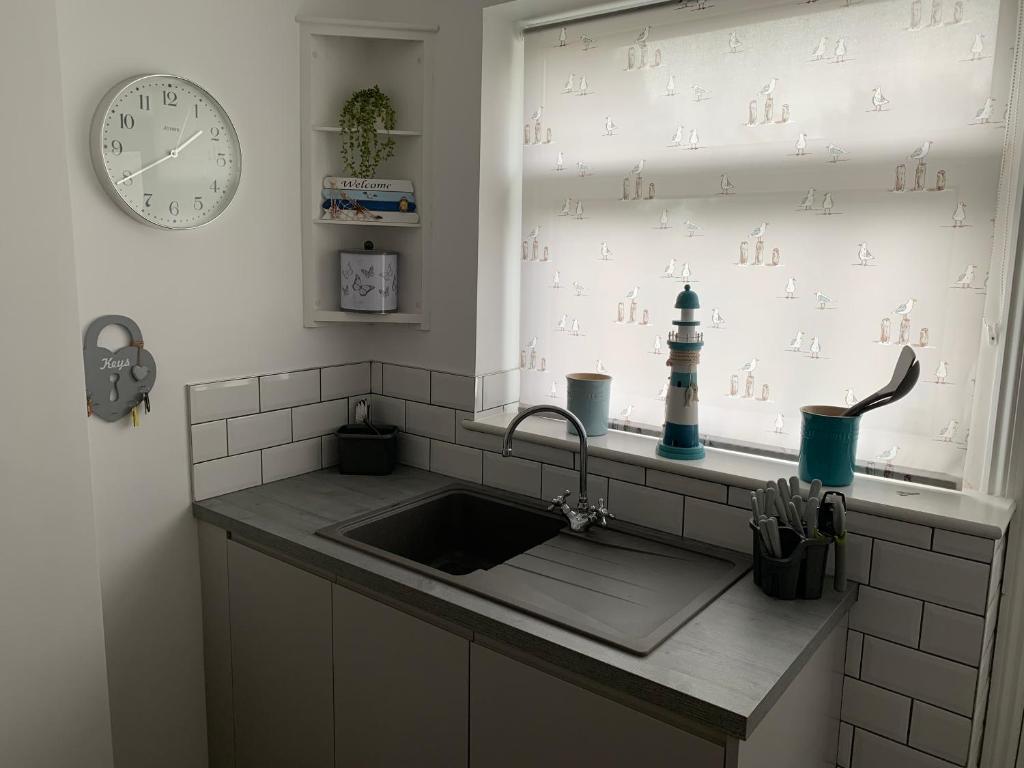 a kitchen with a sink and a clock on the wall at Sea Shells in Greatstone