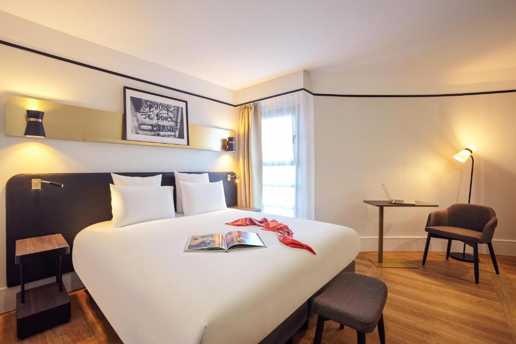 - une chambre d'hôtel avec un grand lit et un livre dans l'établissement Mercure Paris Saint-Ouen, à Saint-Ouen