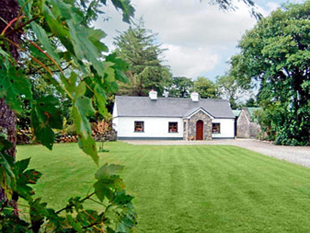a white house with a large yard with a green lawn at Clydagh Lodge in Castlebar
