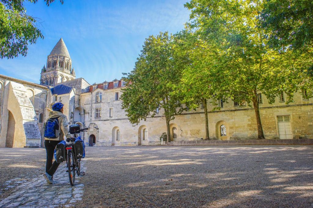 a person riding a bike in front of a building at Les Chambres de l'Abbaye in Saintes