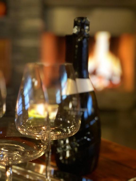 una bottiglia di vino seduta su un tavolo con bicchieri di Magic CHALET near COMO lake, private parking, total privacy I Villa dei Leoni a Morbio Inferiore