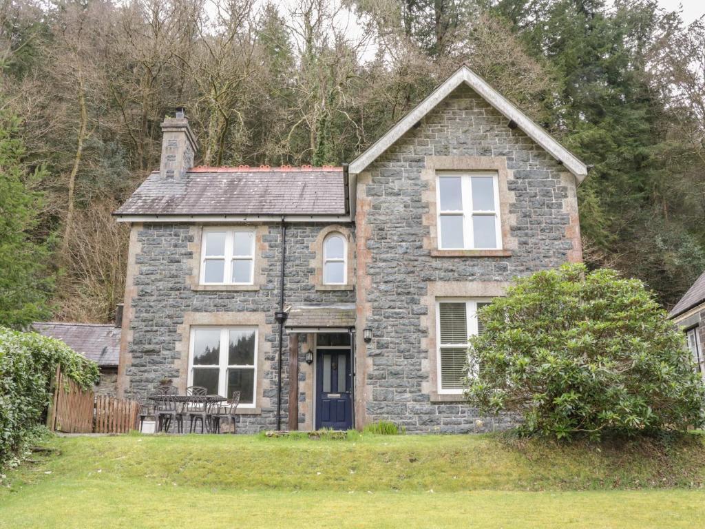 a stone house with a table and chairs in a yard at Ty Capel in Betws-y-coed
