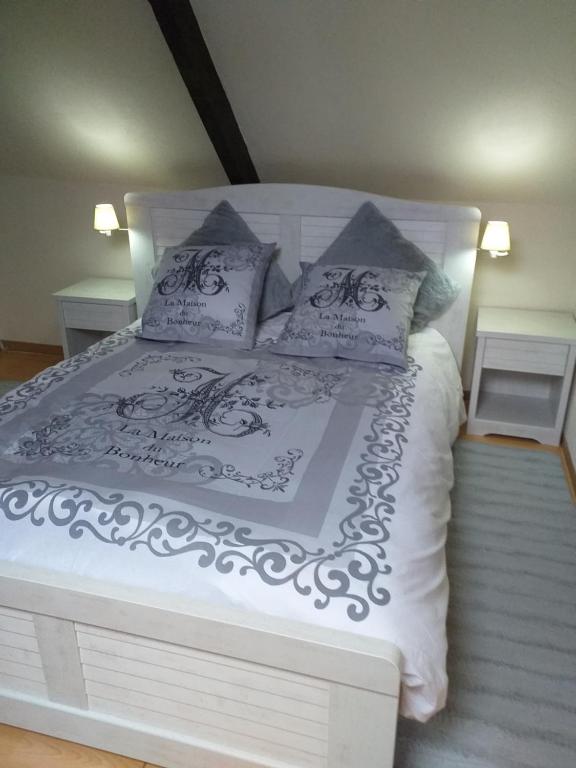 a white bed with a black and white comforter and pillows at LA PETITE MAISON DU SABOT in Langonnet