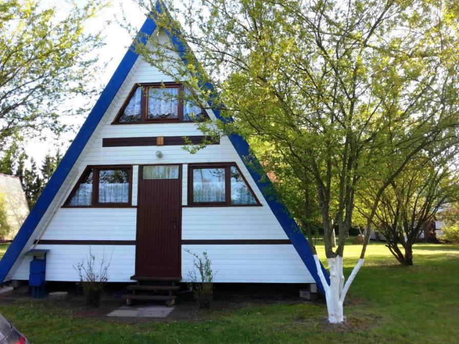 a tiny house with a blue and white roof at Domki Topole in Białogóra