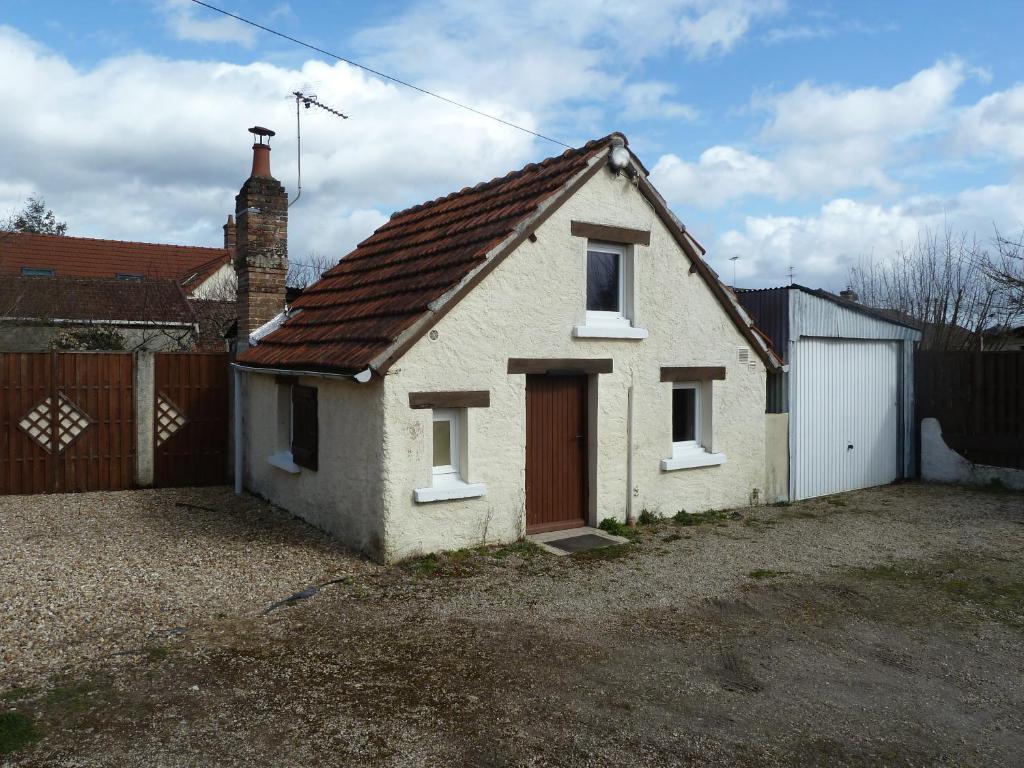 une petite maison blanche avec une porte rouge dans l'établissement La Petite maison en Sologne, à Salbris