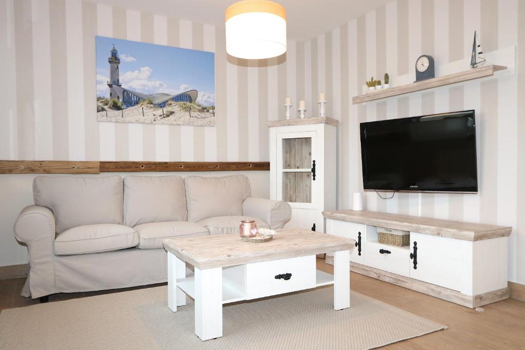 a living room with a white couch and a tv at Haus Ostseenordstern Rerik in Rerik