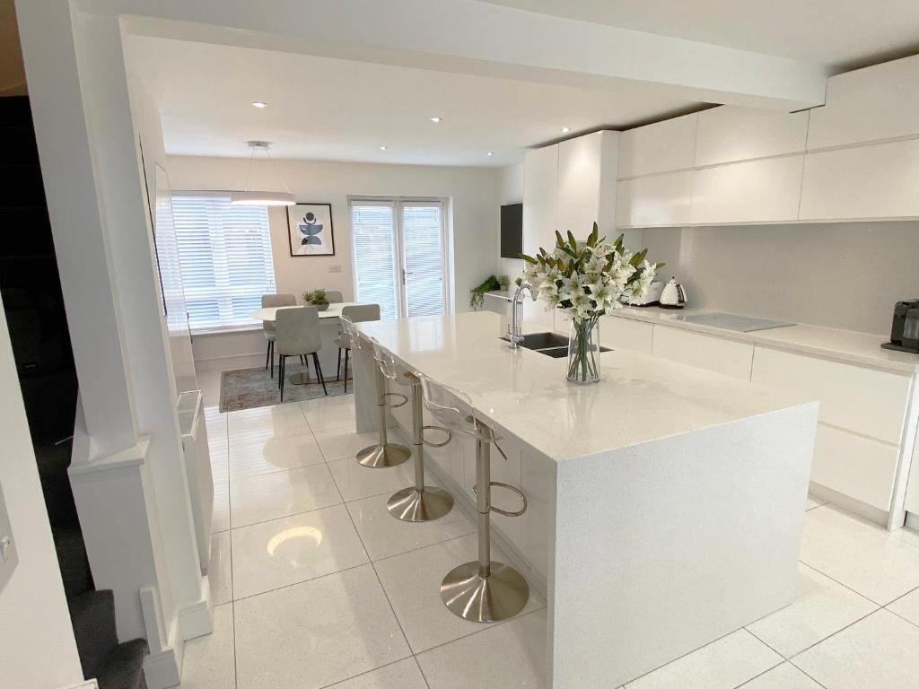a white kitchen with a white counter and a table at Summer House Terrace in Yeovil