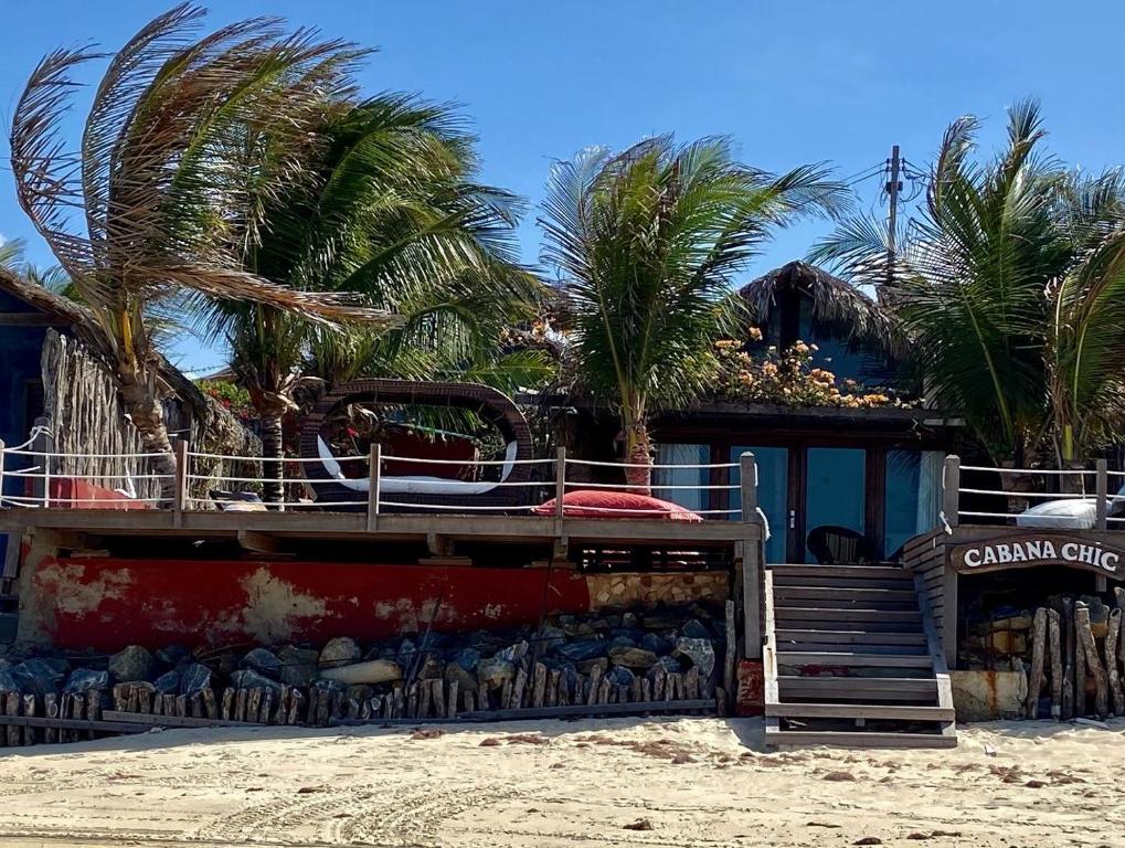 un edificio en la playa con palmeras en el fondo en Cabana Chic, en Tatajuba