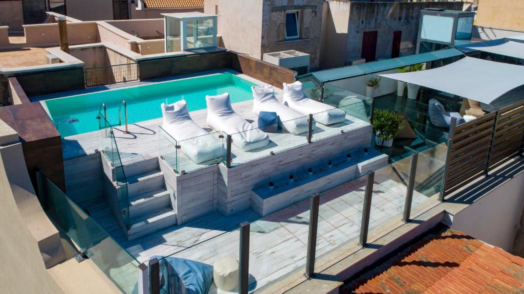 vista sulla piscina con sedie a sdraio bianche di Azzoli Trapani - Apartments&Skypool - Adults Only a Trapani