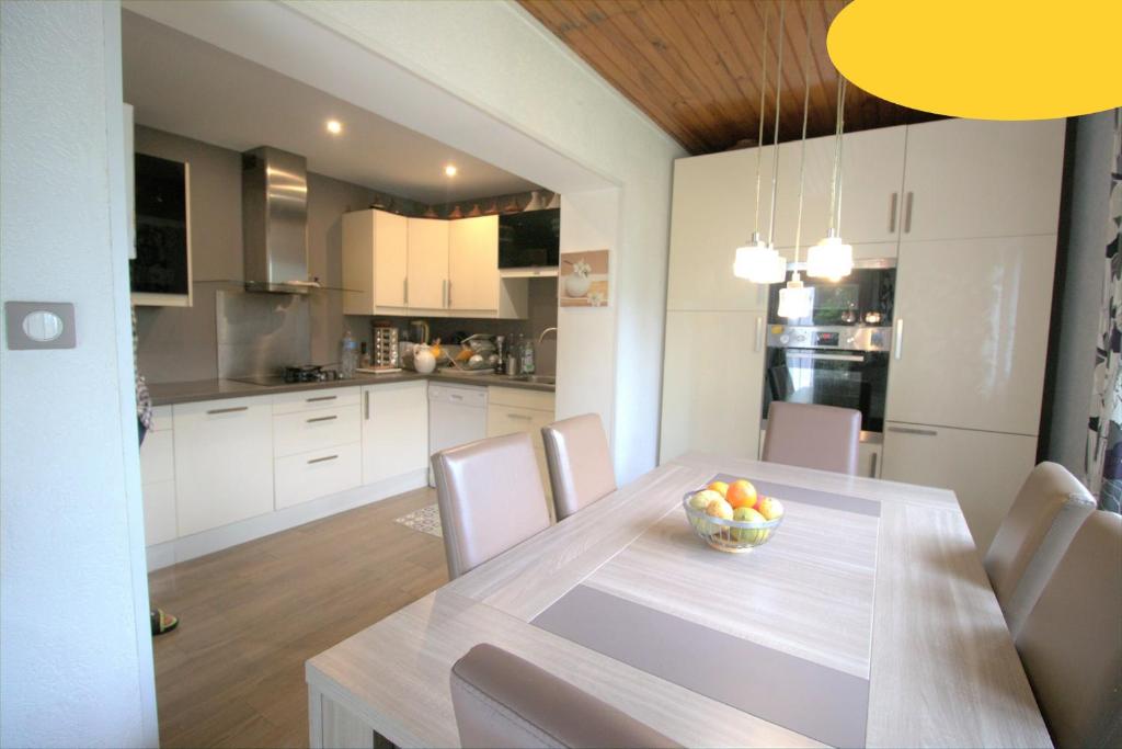 a kitchen and dining room with a table with a bowl of fruit at Jolie chambre Nenuphar dans belle maison in Vaulx-en-Velin