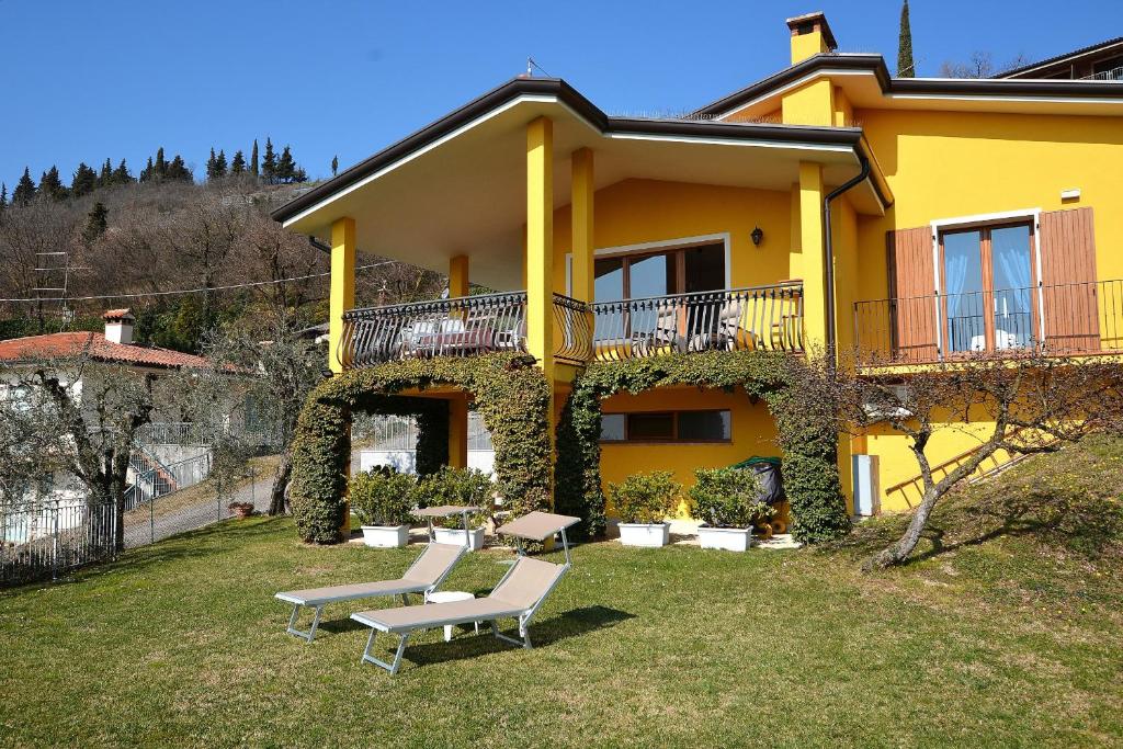 a yellow house with two benches in front of it at Orange Apartment In Marciaga di Costermano in Costermano