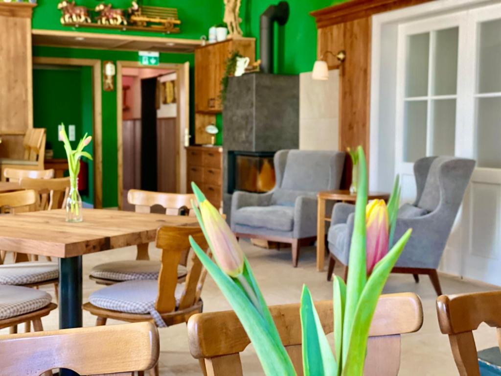 un restaurante con paredes verdes, mesas de madera y sillas en Hotel Waitzingers en Landsberg am Lech