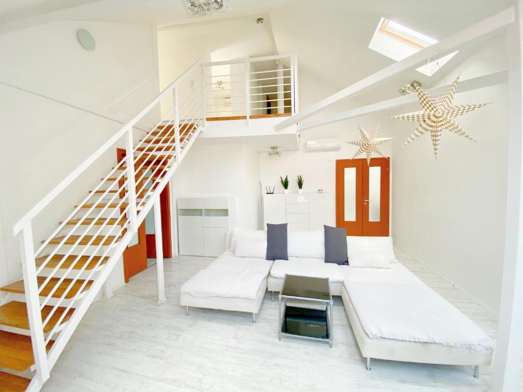 sala de estar blanca con escalera y muebles blancos en Loft with Rooftop and Garage, en Budapest