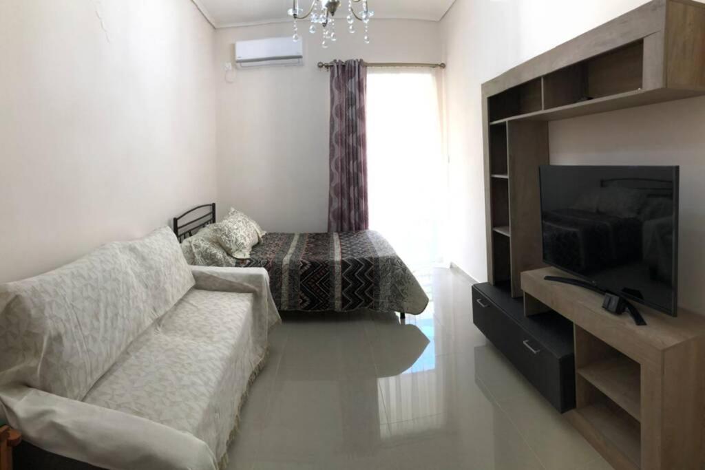 a living room with a couch and a television at Loutraki Vibes Apartments in Loutraki