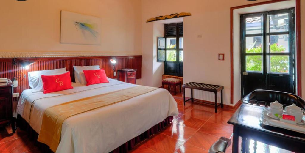 a bedroom with a large bed with red pillows at Hotel Camino Real Popayán Colombia in Popayan