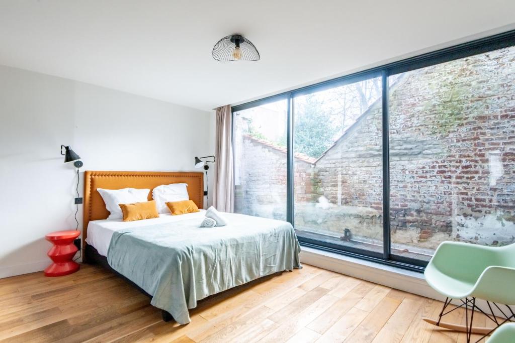 ein Schlafzimmer mit einem Bett und einem großen Fenster in der Unterkunft NOCNOC - Le Ténor, Monnaie in Lille
