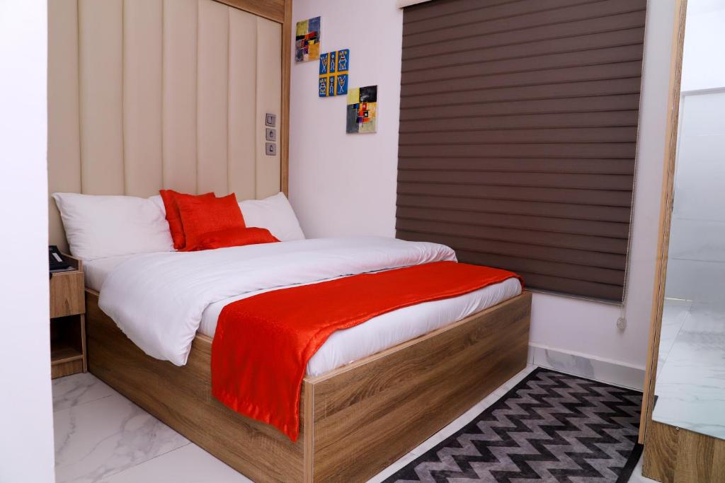 a bedroom with a bed with a red blanket on it at GAZANIA CLASSIC SUITE, RHODABODE APT. in Abuja