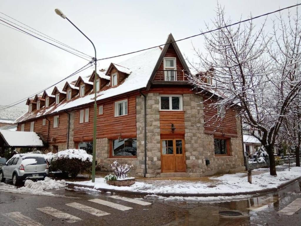 a large wooden house with snow on the roof at Hotel Turismo in San Martín de los Andes