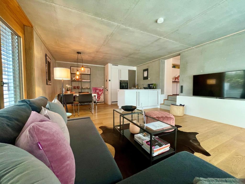 ein Wohnzimmer mit einem Sofa und einem Tisch mit einem TV in der Unterkunft Tolle Ferienwohnung Le Gira mit eigenem Garten in Konstanz