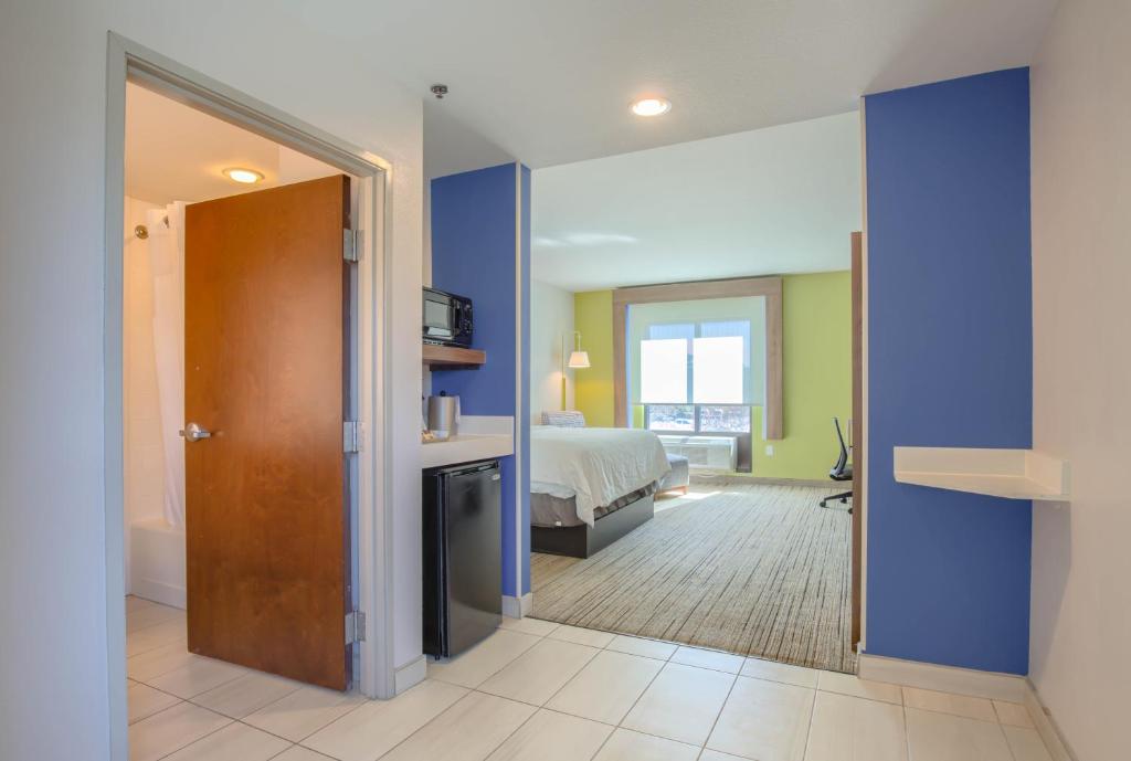 a bedroom with blue walls and a bed and a door at Holiday Inn Express Hotel & Suites Gulf Shores by IHG in Gulf Shores