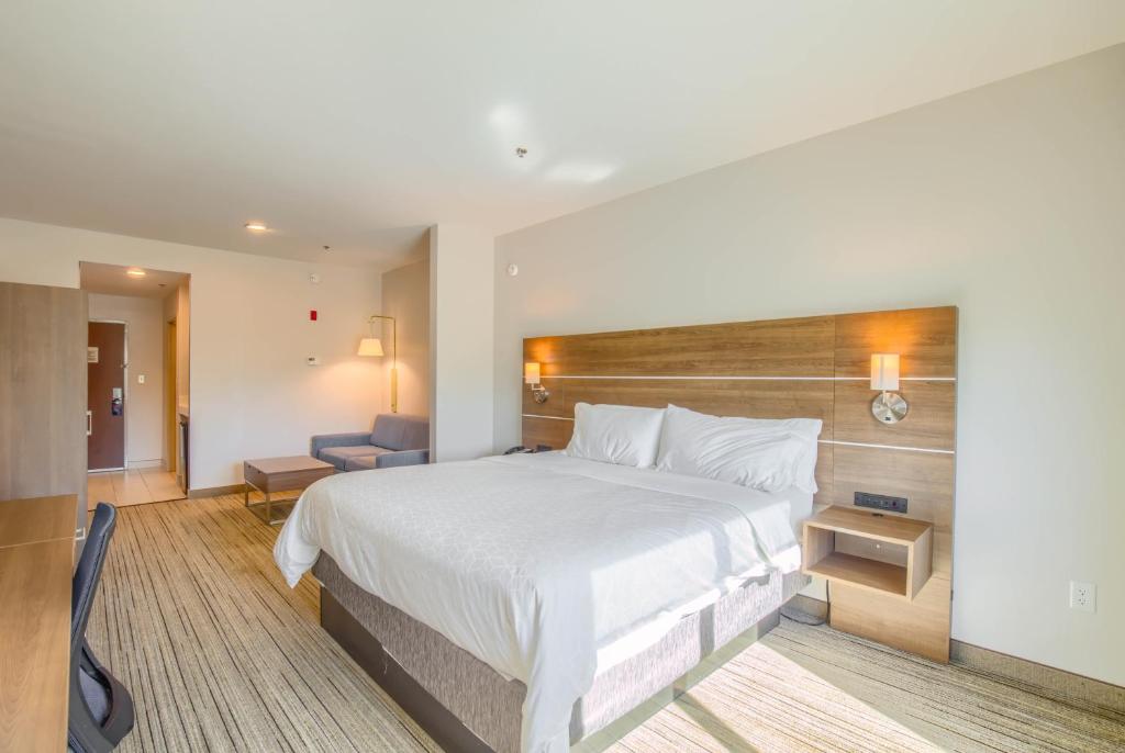 a hotel room with a large bed and a chair at Holiday Inn Express Hotel & Suites Gulf Shores by IHG in Gulf Shores