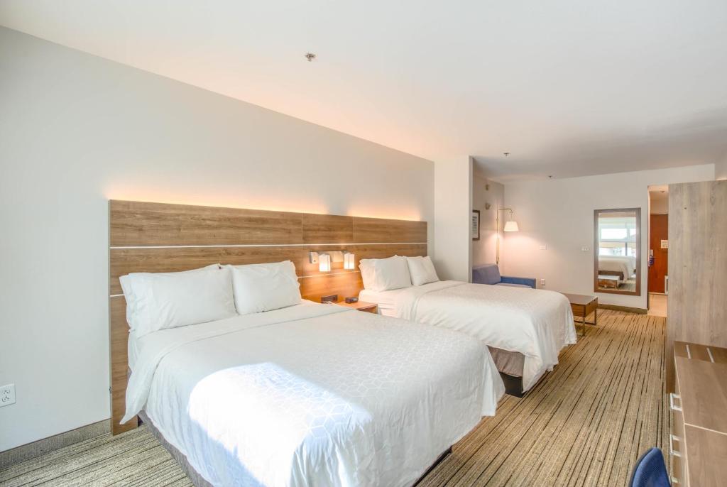 two beds in a hotel room with white sheets at Holiday Inn Express Hotel & Suites Gulf Shores by IHG in Gulf Shores