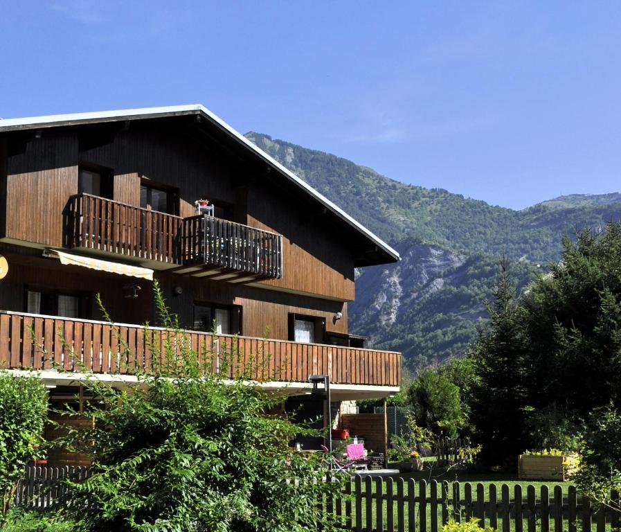 un edificio in legno con balcone e montagne sullo sfondo di Chalet la Cachette Cyclists & Skiers a Le Bourg-dʼOisans