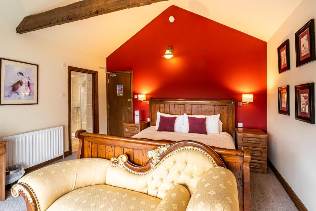 um quarto com uma cama com uma parede vermelha em The Village Inn em Longframlington