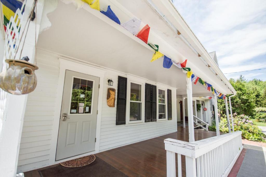 a white house with a porch with flags on it at The Notch Hostel in North Woodstock