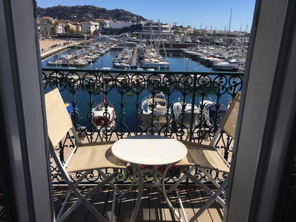 uma mesa e cadeiras numa varanda com uma marina em Luxury 1 bedroom Quai St Pierre 2 mins from the Palais & Croisette 269 em Cannes