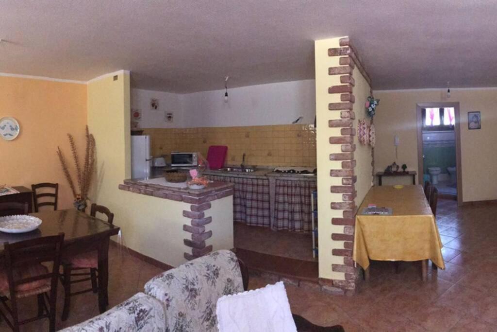 a living room with a kitchen and a living room with a brick wall at Appartamento accogliente in Siniscola
