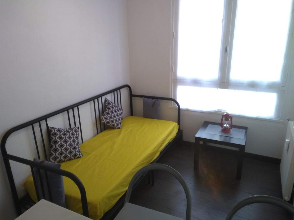 ドゥアルヌネにあるStudio Port Rhu Douarnenezの黄色のベッドとテーブルが備わる小さな客室です。