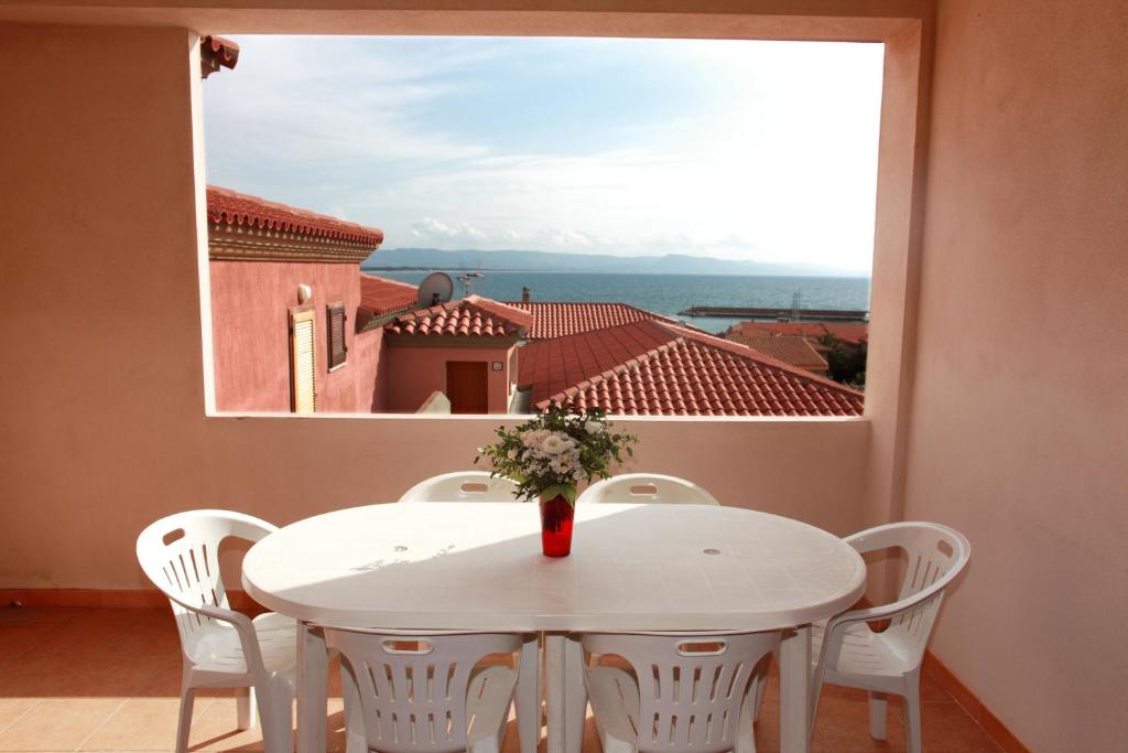 a white table and chairs on a balcony with a large window at Appartamenti Ideal in Isola Rossa