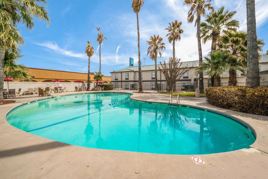 a large swimming pool with palm trees and a building at Motel 6-Laredo, TX - North I-35 in Laredo