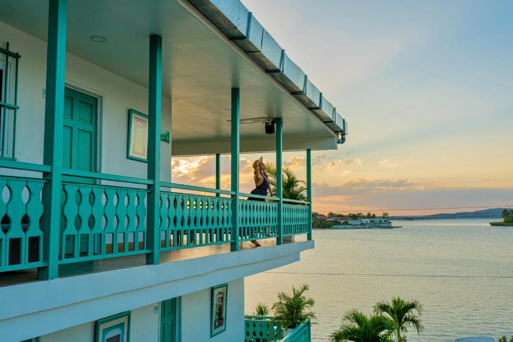 uma mulher de pé numa varanda com vista para a água em Hotel Casa Turquesa em Flores