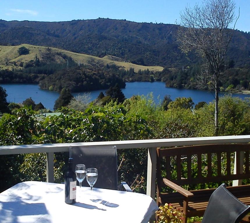 a table with wine glasses on a balcony with a view of a lake at The Tuai Suite Waikaremoana in Tuai