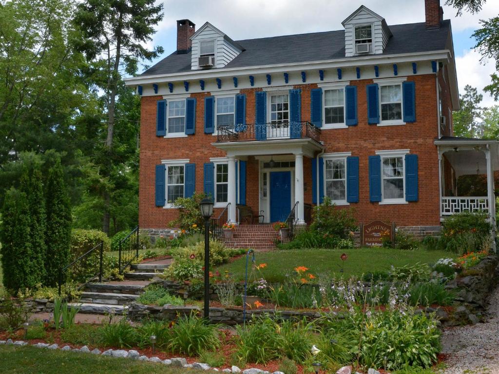 uma antiga casa de tijolos com persianas azuis e um jardim em Lightner Farmhouse B&B em Gettysburg