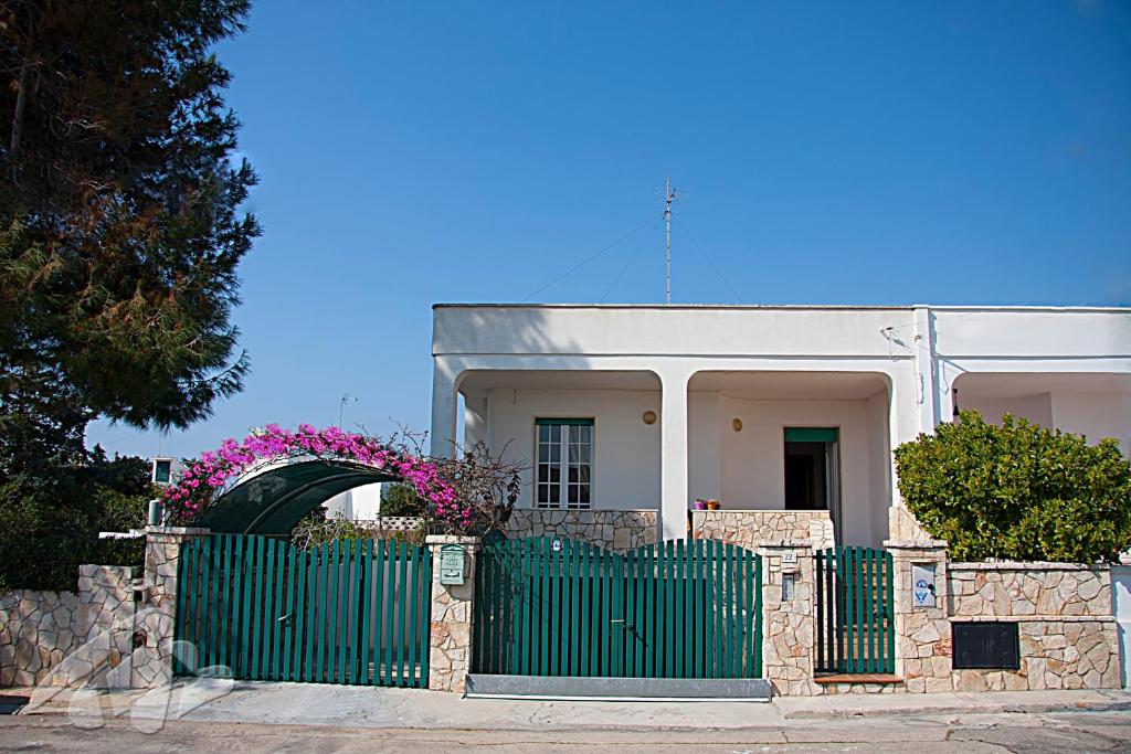 uma cerca verde em frente a uma casa branca em Villetta Lungomare Gallipoli - Family House em Marina di Mancaversa