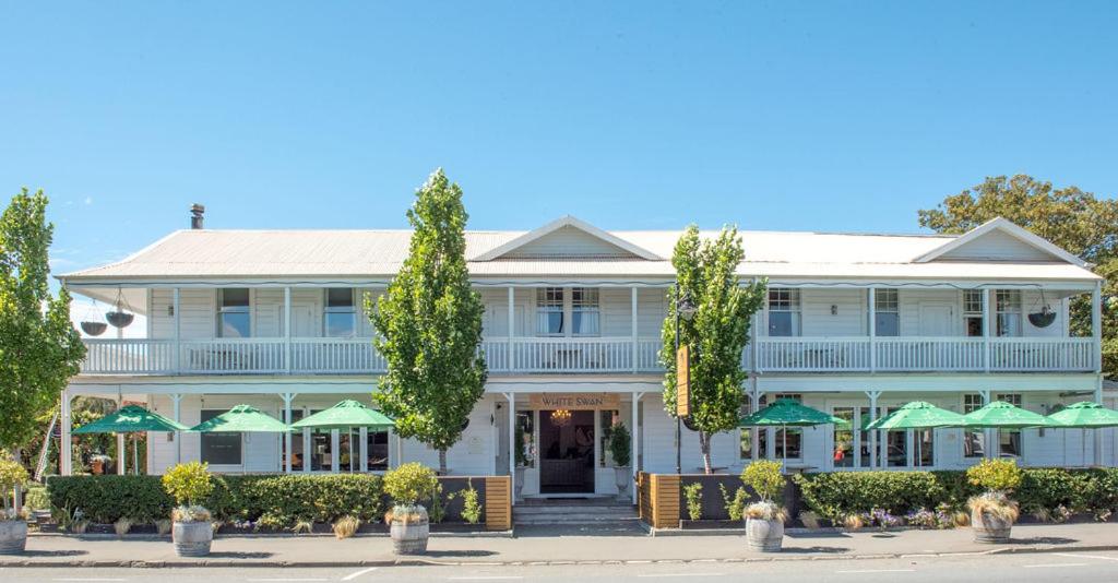 una gran casa blanca con sombrillas verdes en The White Swan Hotel en Greytown