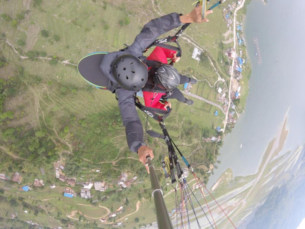 una persona è appesa a un paracadute con uno snowboard di Pushpa Guest House a Pokhara