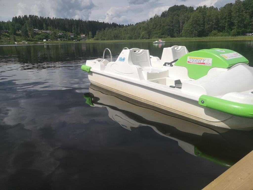 a white boat with an umbrella sitting on the water at Vimmerby Camping in Vimmerby