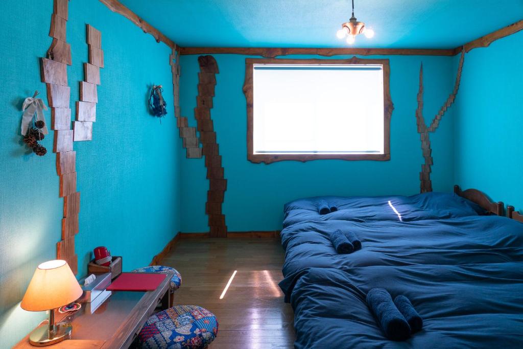 een kamer met blauwe muren, een bed en een raam bij Lodge Mondo in Nishina