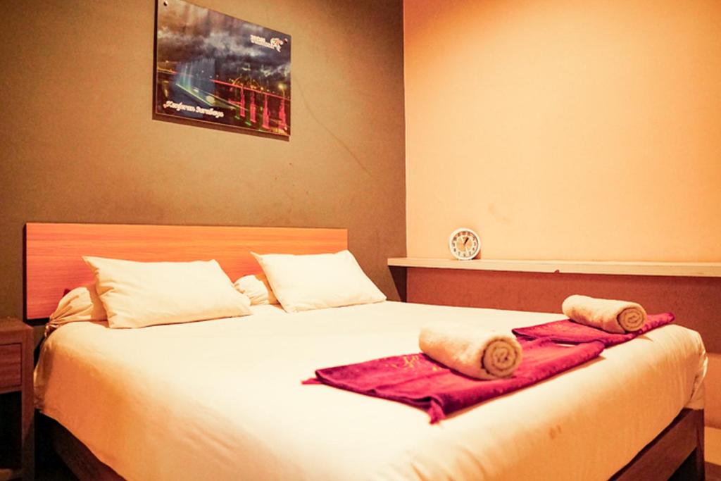 1 dormitorio con 1 cama con toallas en Audah Syariah Residence Mitra RedDoorz, en Surabaya