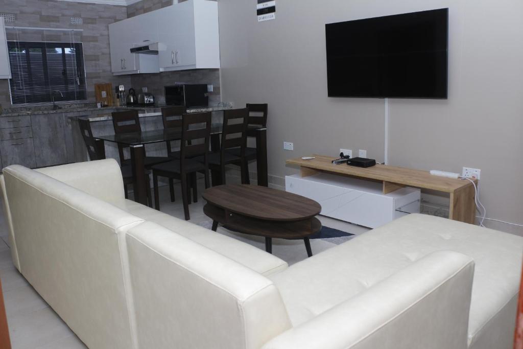 Royal Luxury Hotels and Apartments في Kitwe: غرفة معيشة مع أريكة بيضاء وطاولة
