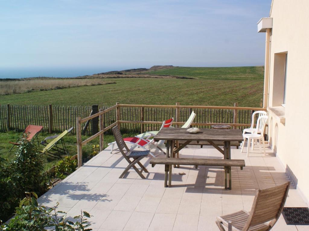 eine Terrasse mit einem Holztisch und Stühlen auf dem Balkon in der Unterkunft Wonderful holiday home in Audinghen with garden in Audinghen