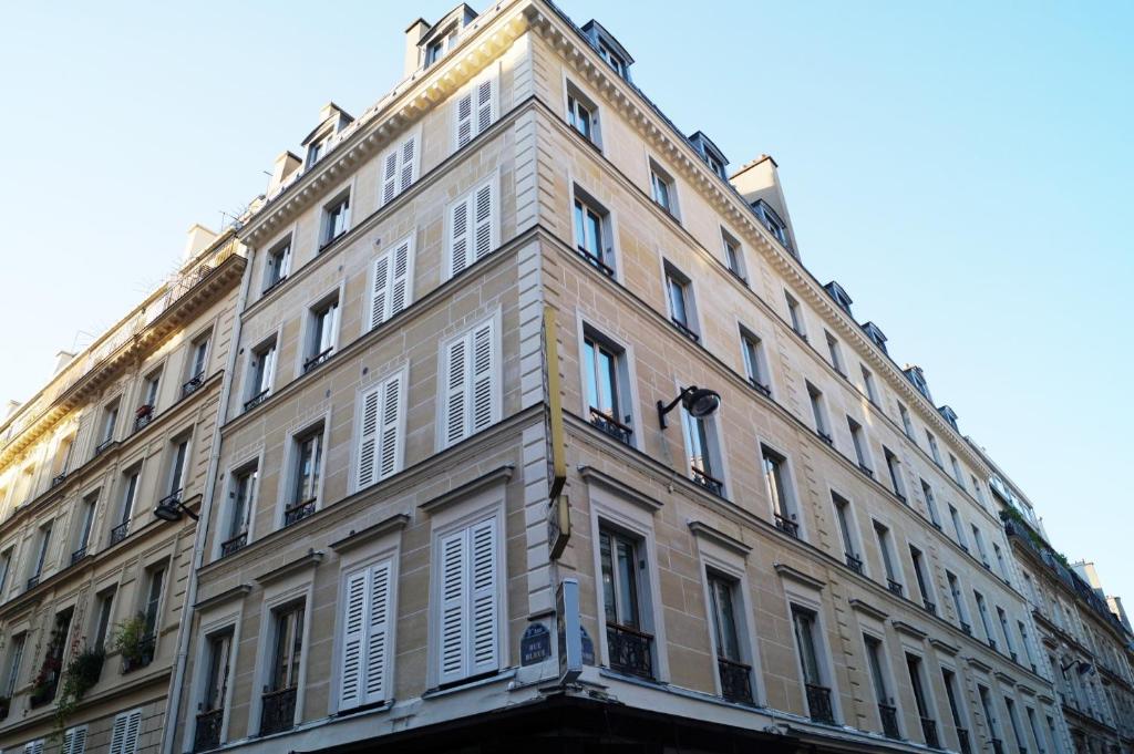 パリにあるHotel Havane Operaの白いシャッターが付いた大きなレンガ造りの建物